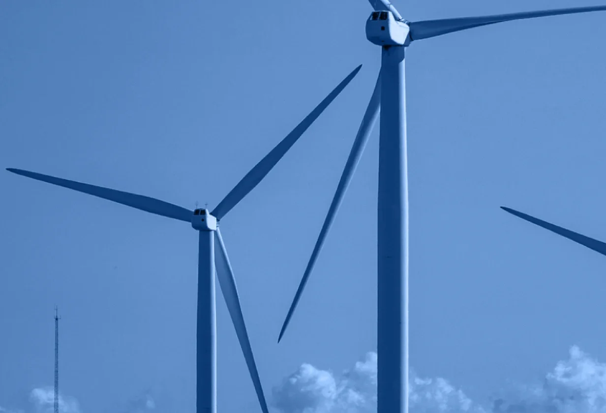 Two large wind turbines with three blades each stand against a blue sky, their clean energy symbolizing the future of both home and industry. Clouds gather near the bottom, while a cool blue tone unifies the serene scene.