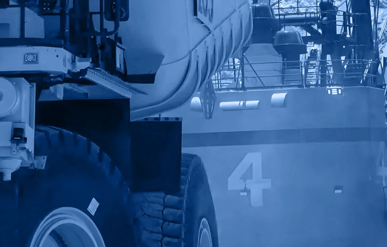 Large industrial vehicle tires and machinery in the foreground evoke a strong industry accordion theme, with the number 4 visible on a blue-tinted structure in the background.